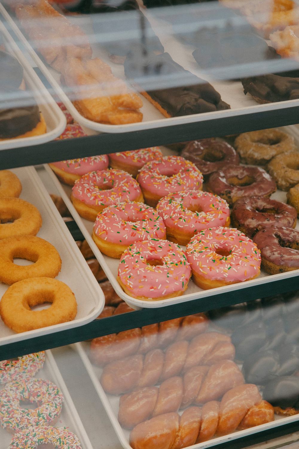 Trays of pink-frosted and glazed donuts in the Randy's Donuts case